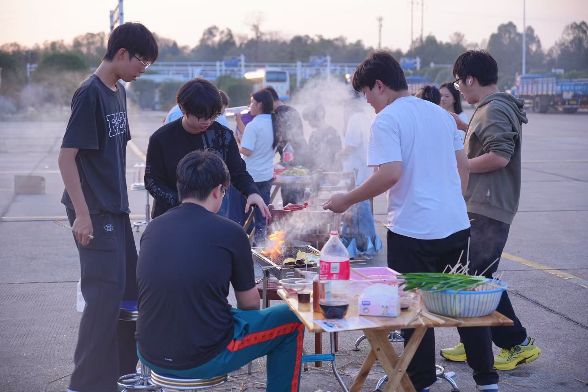往期活动中同学们围坐烤炉旁，炭火与烟气映出青春的热闹